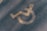 A faded yellow wheelchair symbol is painted on a textured asphalt surface, often seen in parking areas reserved for individuals with disabilities.