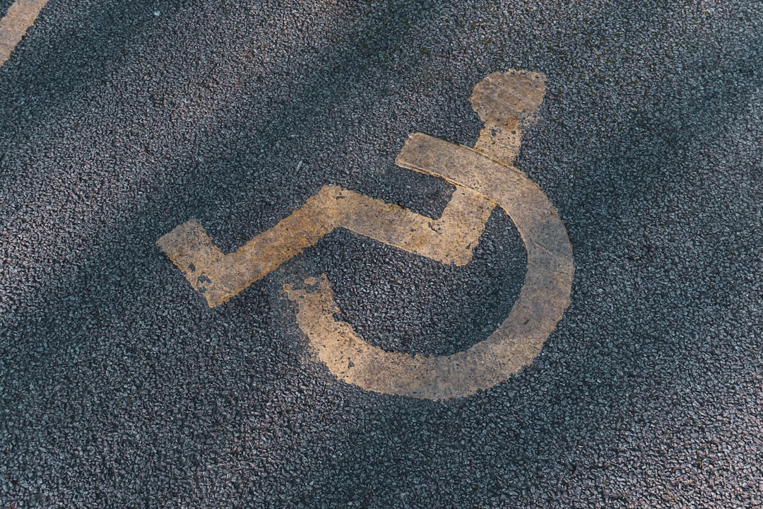 a handicapped sign painted on the asphalt of a parking lot, Disabled parking. Accessible parking spot. Blue badge. Yello