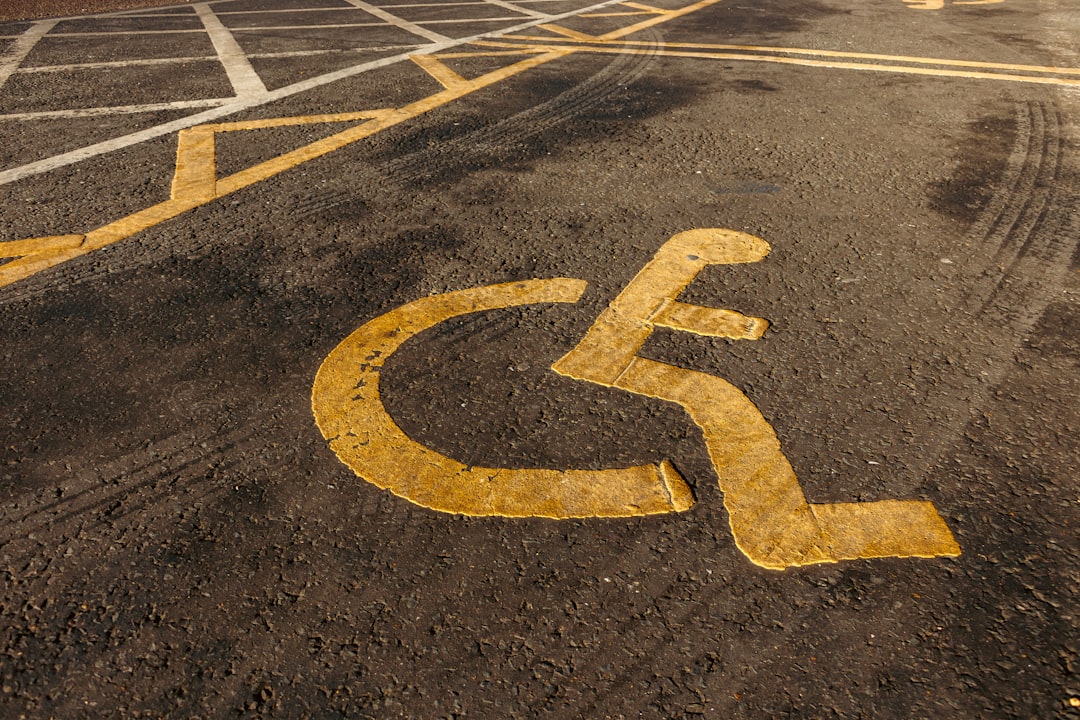 a handicapped sign painted on a parking lot, Disabled parking. Accessible parking spot. Blue badge. Yellow wheelchair si