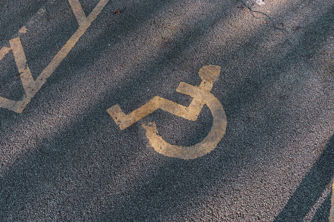 a handicapped sign painted on the asphalt of a street, Disabled parking. Accessible parking spot. Blue badge. Yellow whe