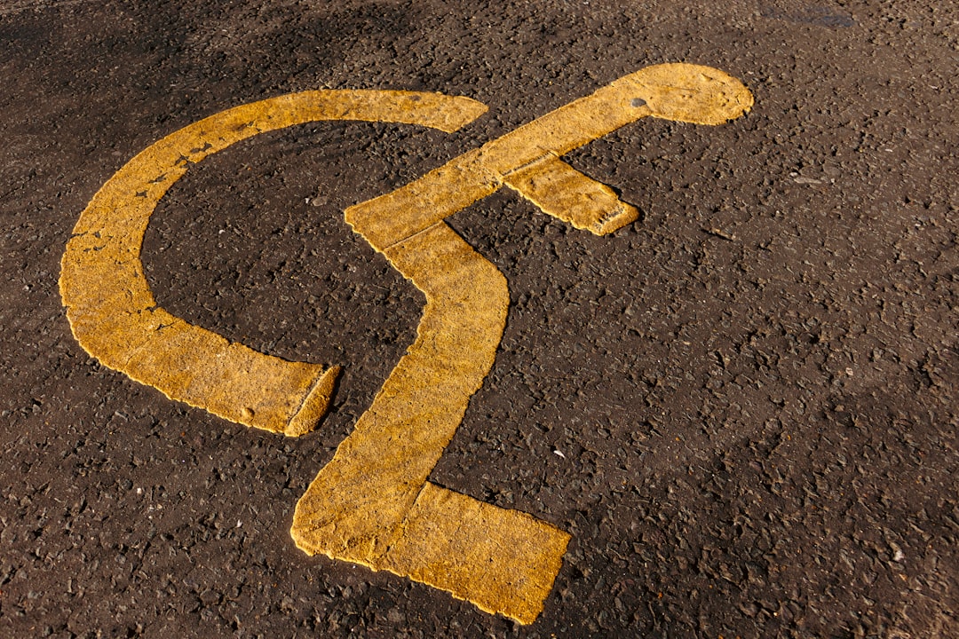 a yellow arrow painted on the ground in the middle of the road, Disabled parking. Accessible parking spot. Blue badge. Y