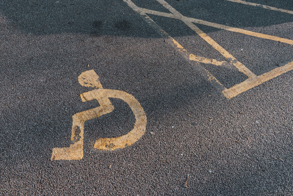 a handicapped sign painted on the asphalt of a parking lot