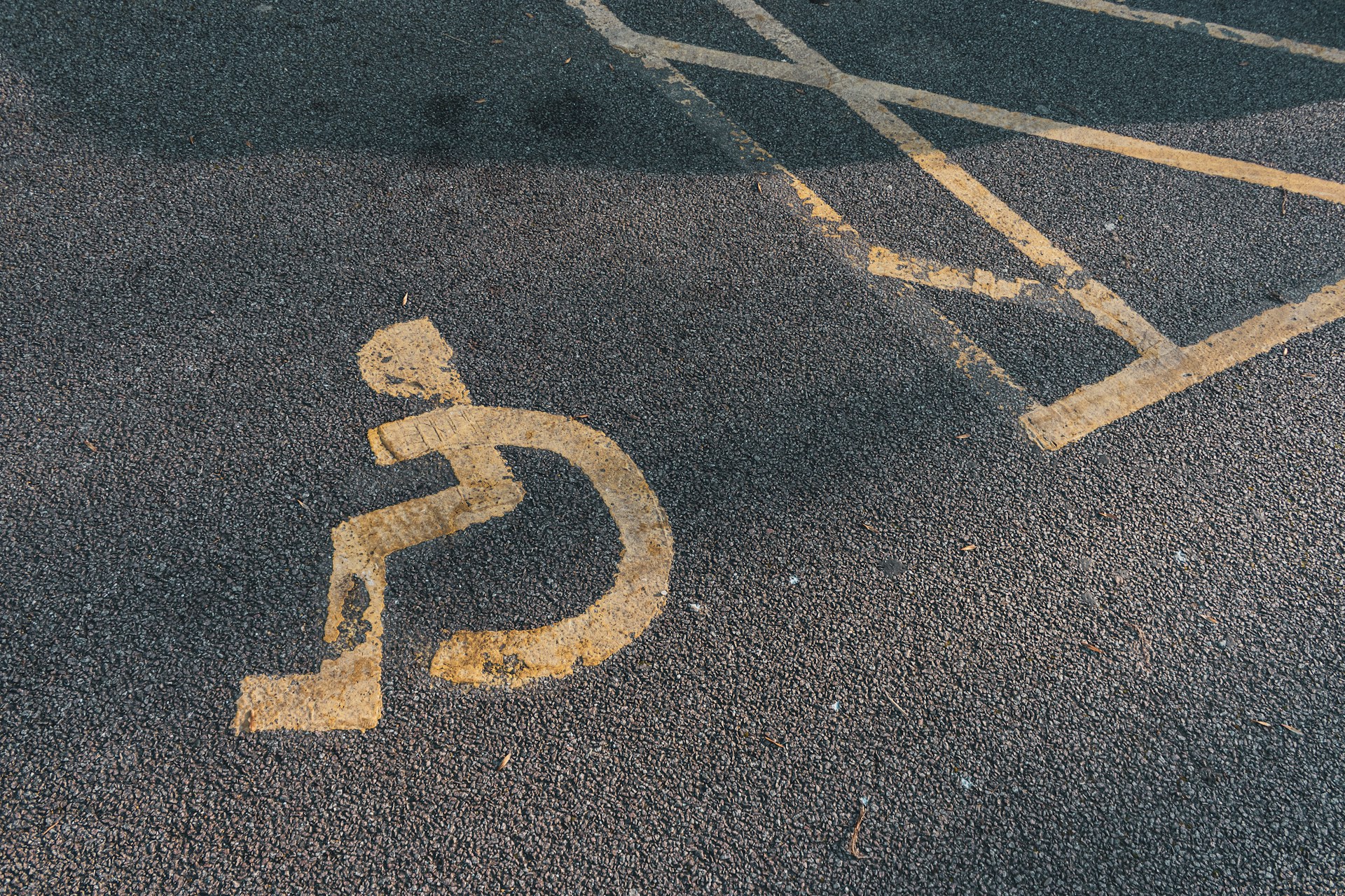 a handicapped sign painted on the asphalt of a parking lot
