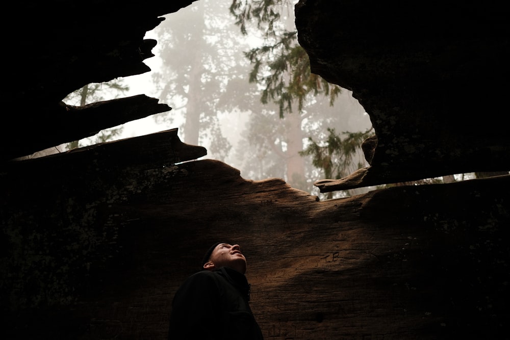 a man standing in a cave looking up at the sky