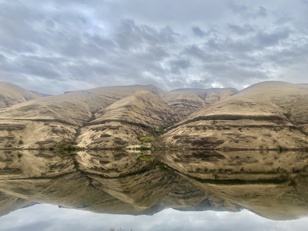 a mountain range is reflected in the still water of a lake