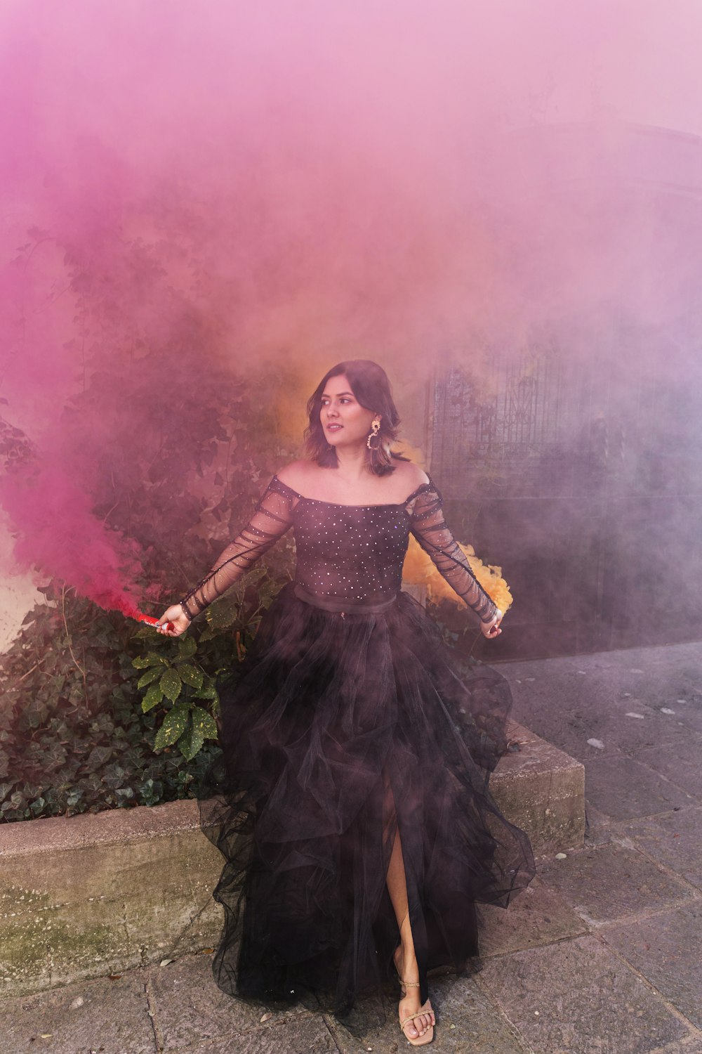 Une femme vêtue d'une longue robe noire tenant une bombe fumigène