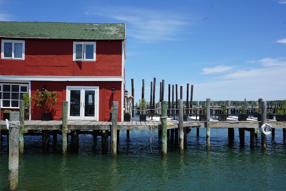 a red house sitting on top of a wooden pier