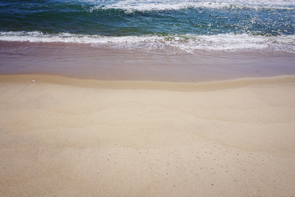 a sandy beach with waves coming in to shore