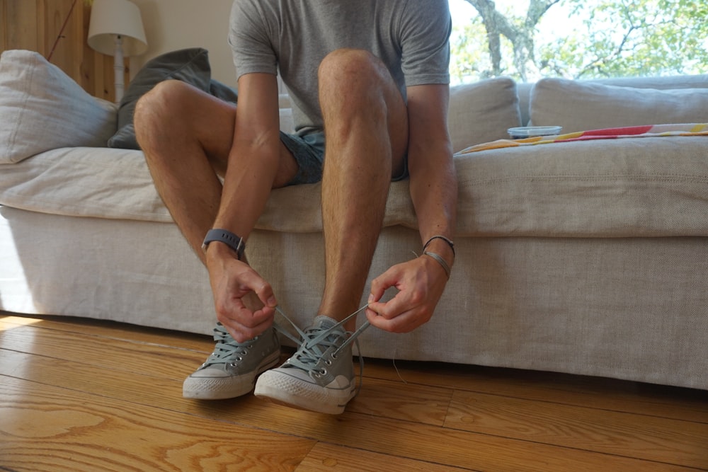 a man sitting on a couch holding his shoes