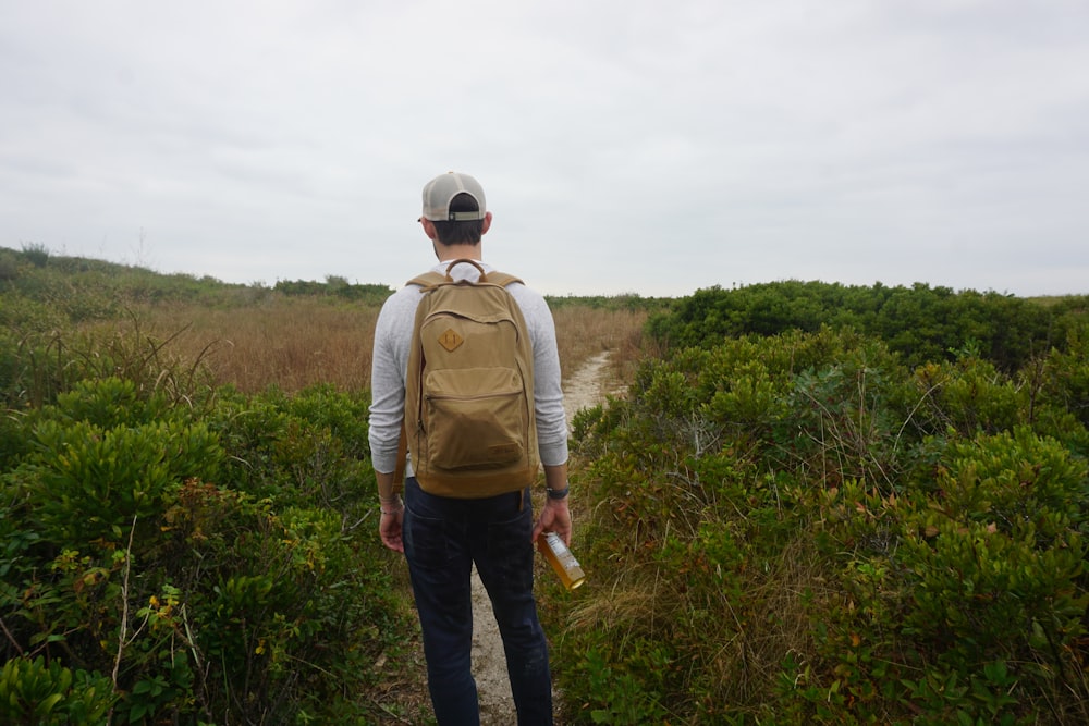 a man standing in a field with a backpack on his back