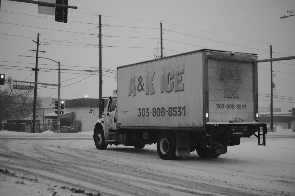 a truck driving down a snow covered street