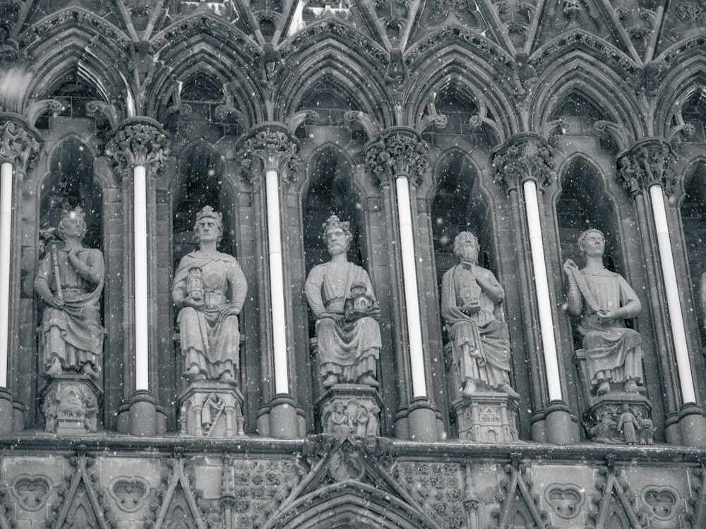 a black and white photo of statues on a building