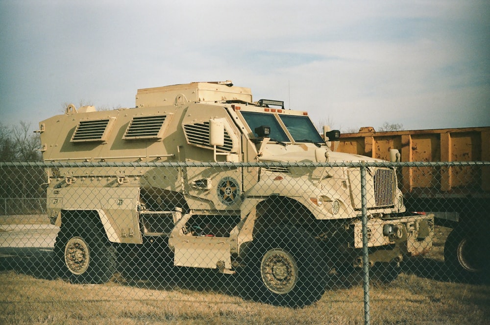 a military vehicle parked behind a chain link fence