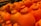 A close-up view of a pile of bright orange citrus fruits, likely oranges or a similar variety, with a distinct navel-like formation on the top. The fruits appear fresh and are stacked closely together, indicating they are on display, possibly in a market or grocery store.