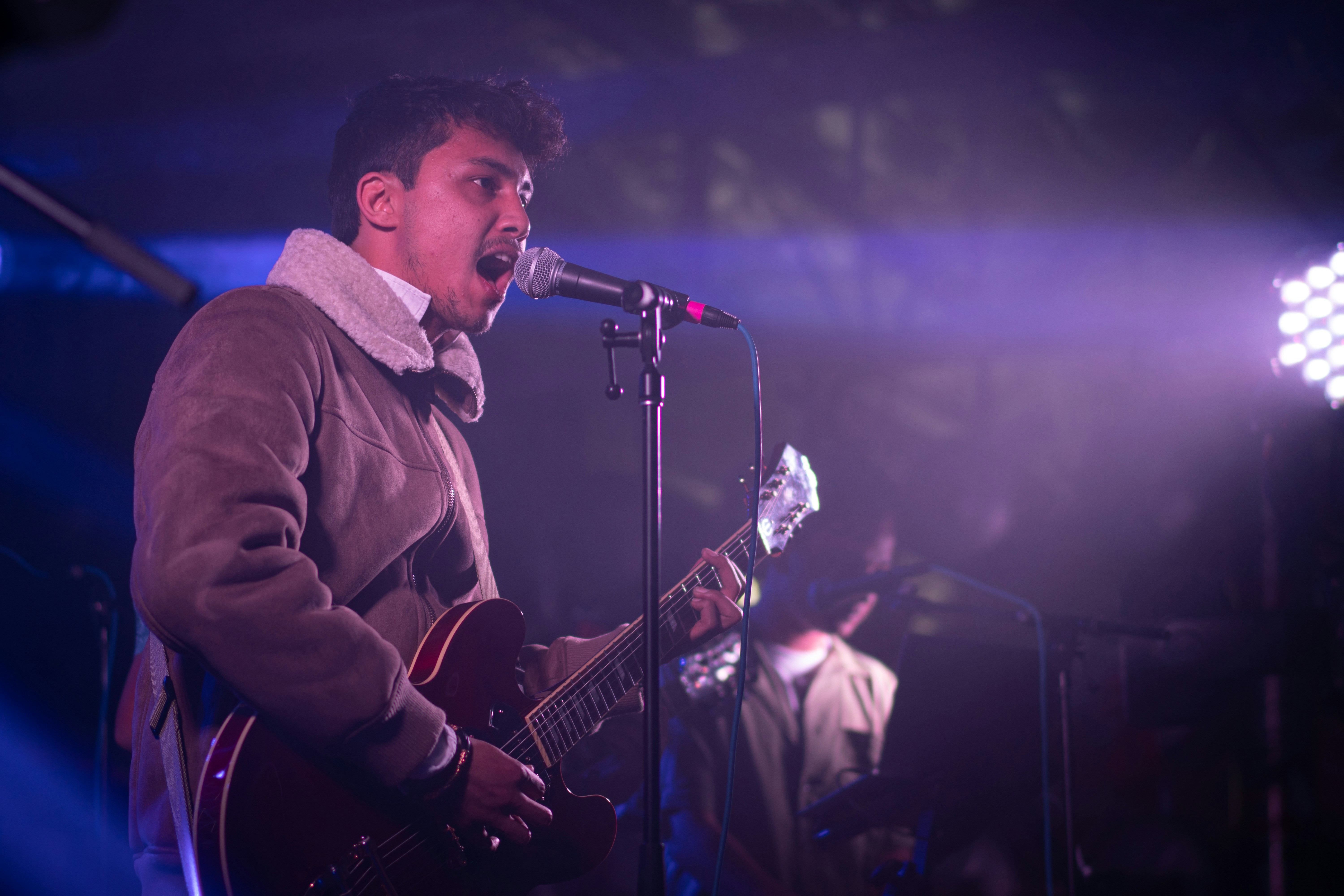a man singing into a microphone while holding a guitar
