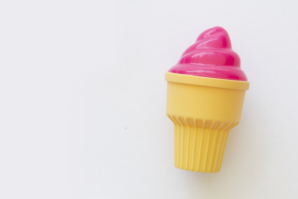 a yellow cupcake with a pink frosting on top