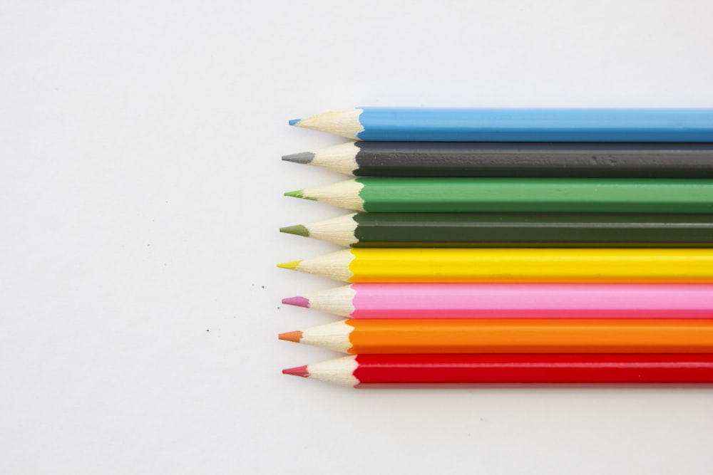 a group of colored pencils lined up on a white surface