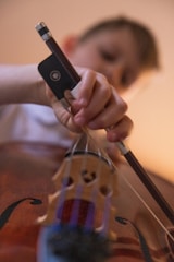 a child is playing a violin with a cell phone