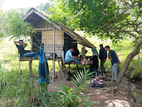 A modern off-grid community center surrounded by trees and natural landscaping, with people gathering outdoors.