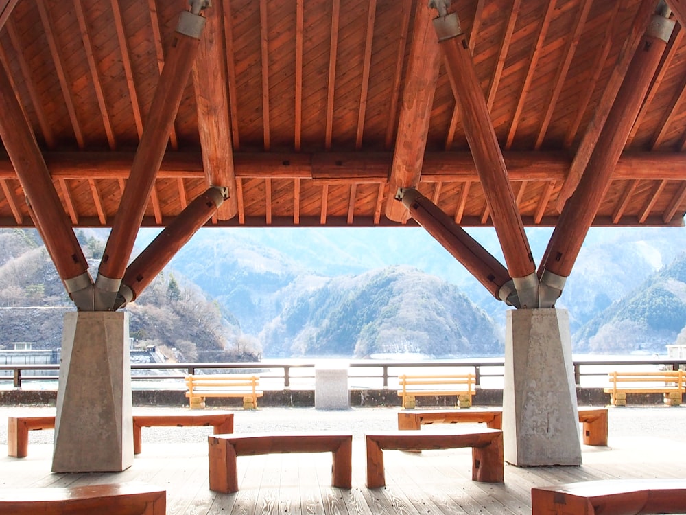 a covered area with benches and mountains in the background