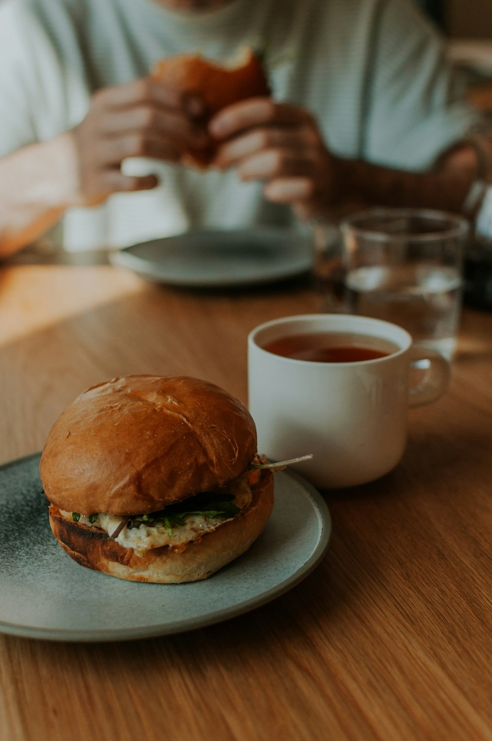 a person sitting at a table with a sandwich and a cup of tea