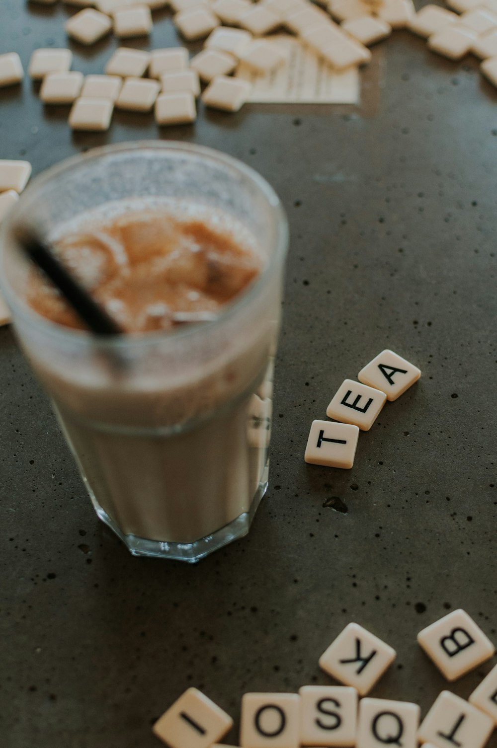 a cup of coffee sitting on top of a table next to scrabbles