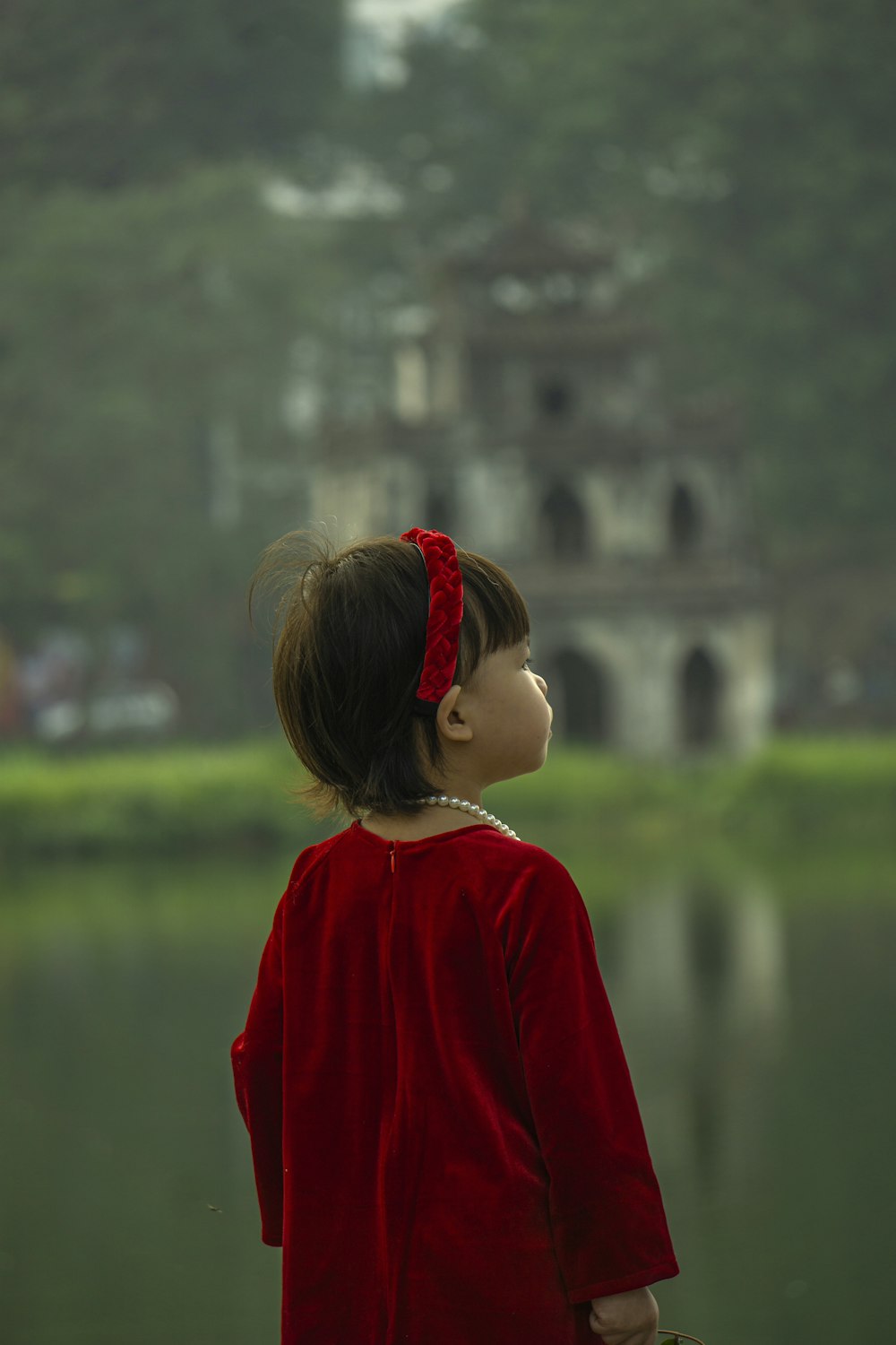 uma menina em pé na frente de um corpo de água