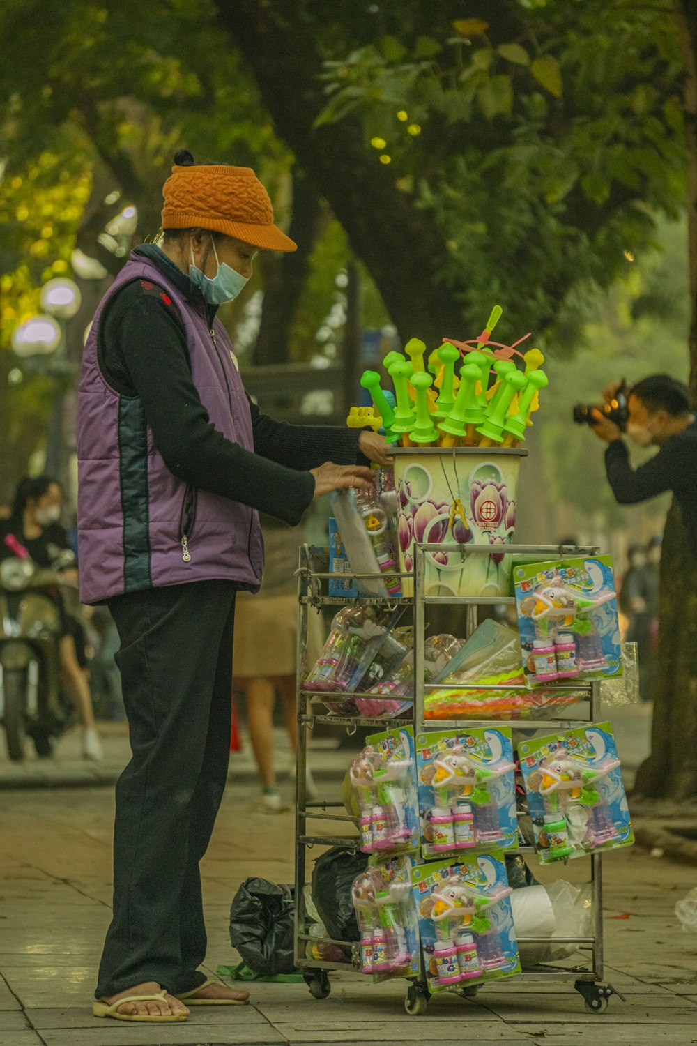 a man in a purple vest and orange hat is pushing a cart full of items