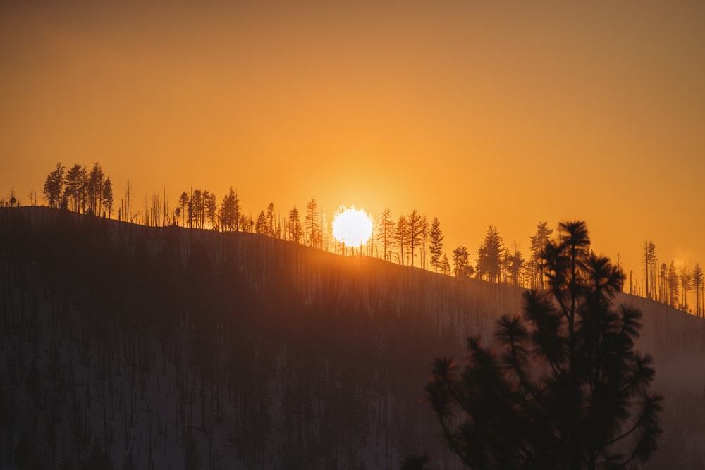 the sun is setting over a snowy mountain