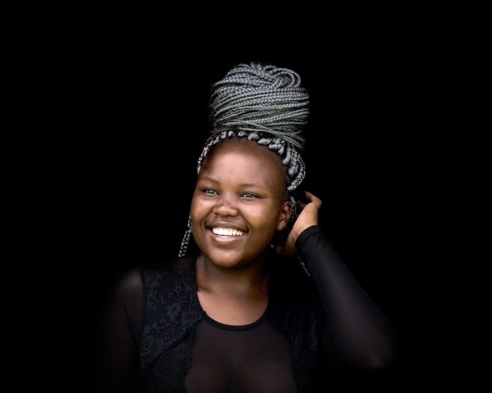 a smiling woman wearing a black top and a silver head wrap