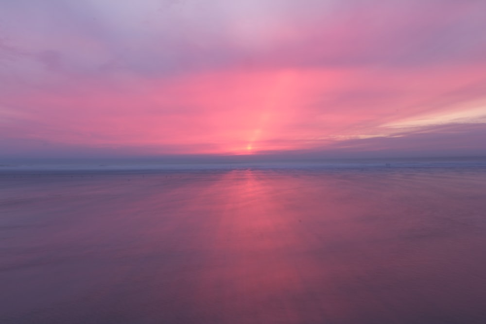 the sun is setting over the water at the beach