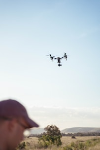 a man standing in a field looking at a flying object