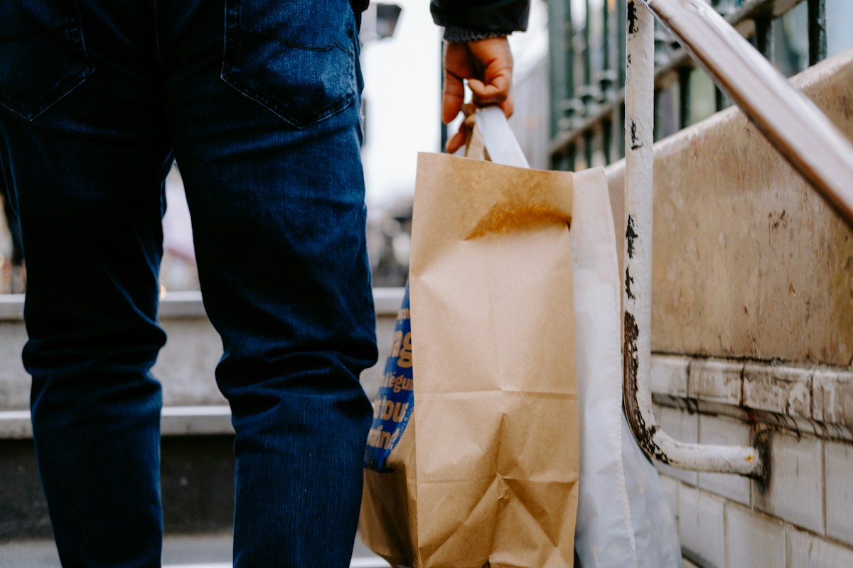 A man carrying a brown paper bag down stairs, illustrating community meal train sign-up in action.