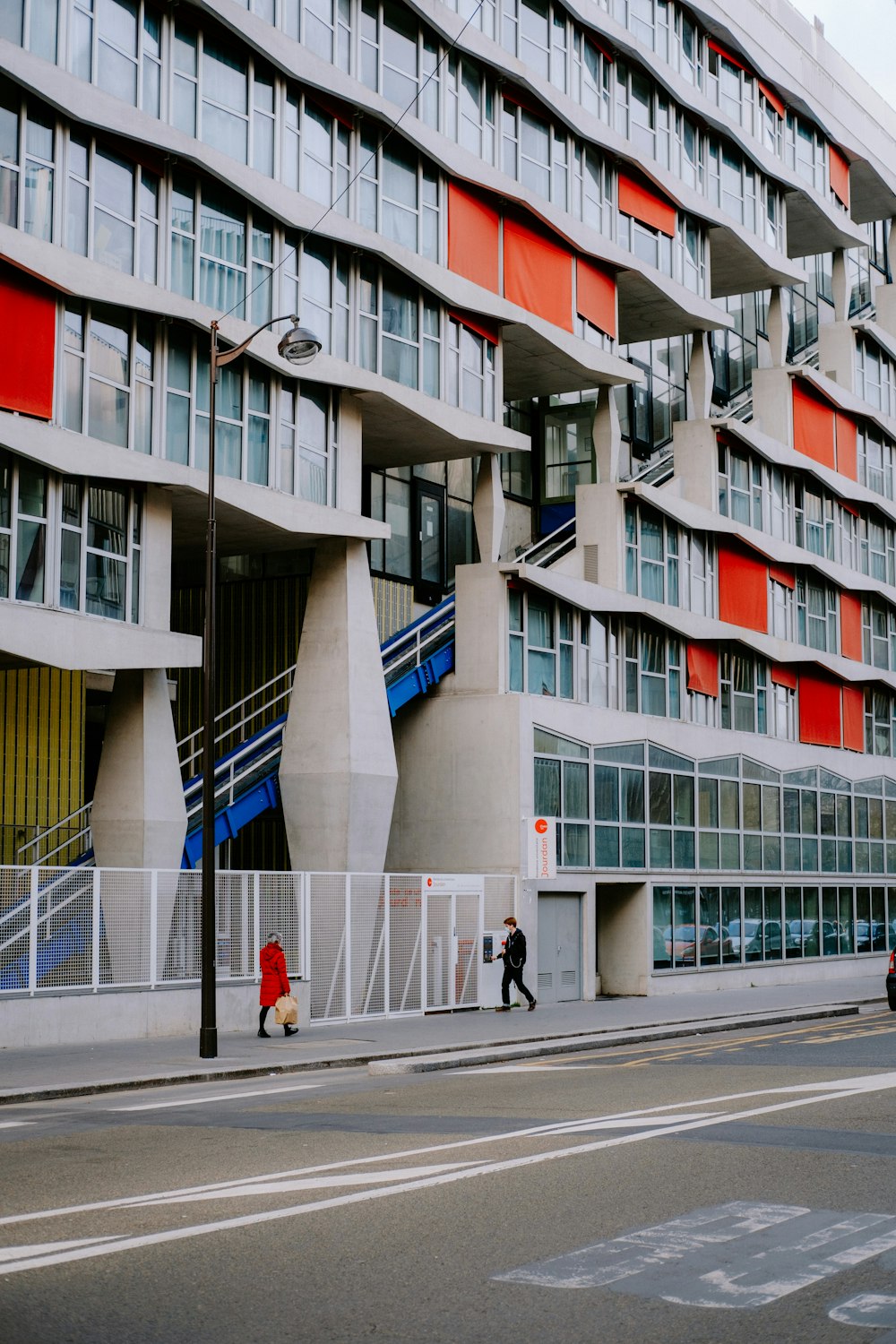 two people walking on a sidewalk in front of a building