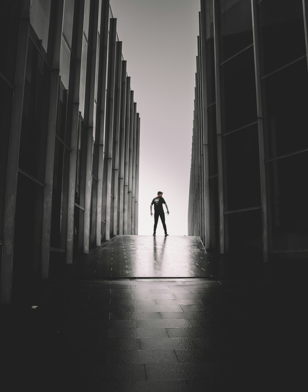 a man standing in a hallway between two tall buildings