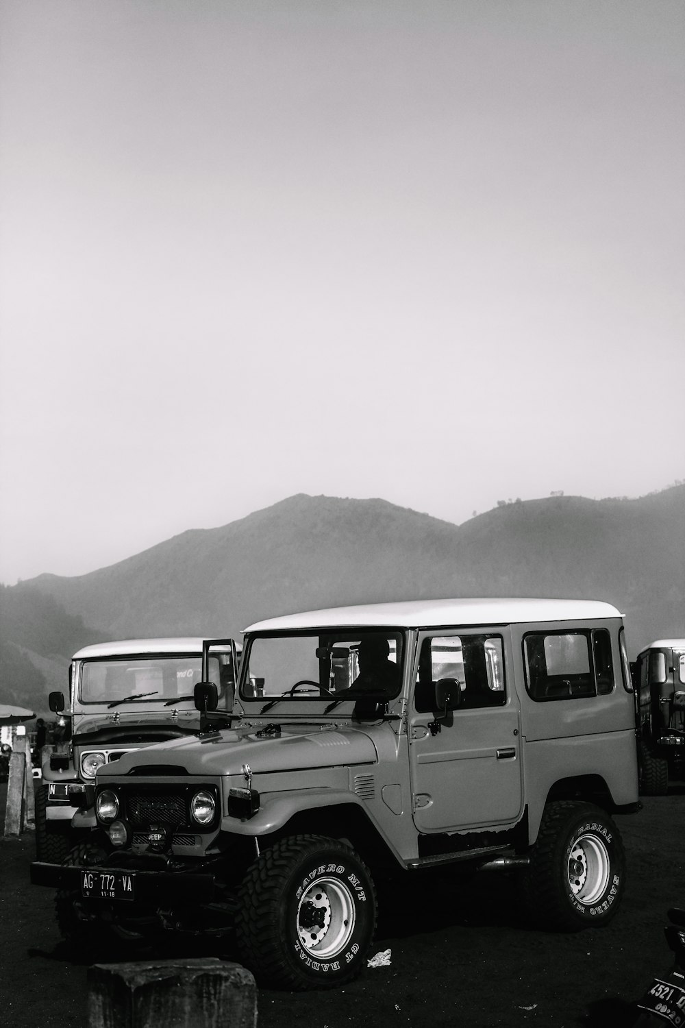 a black and white photo of a line of jeeps