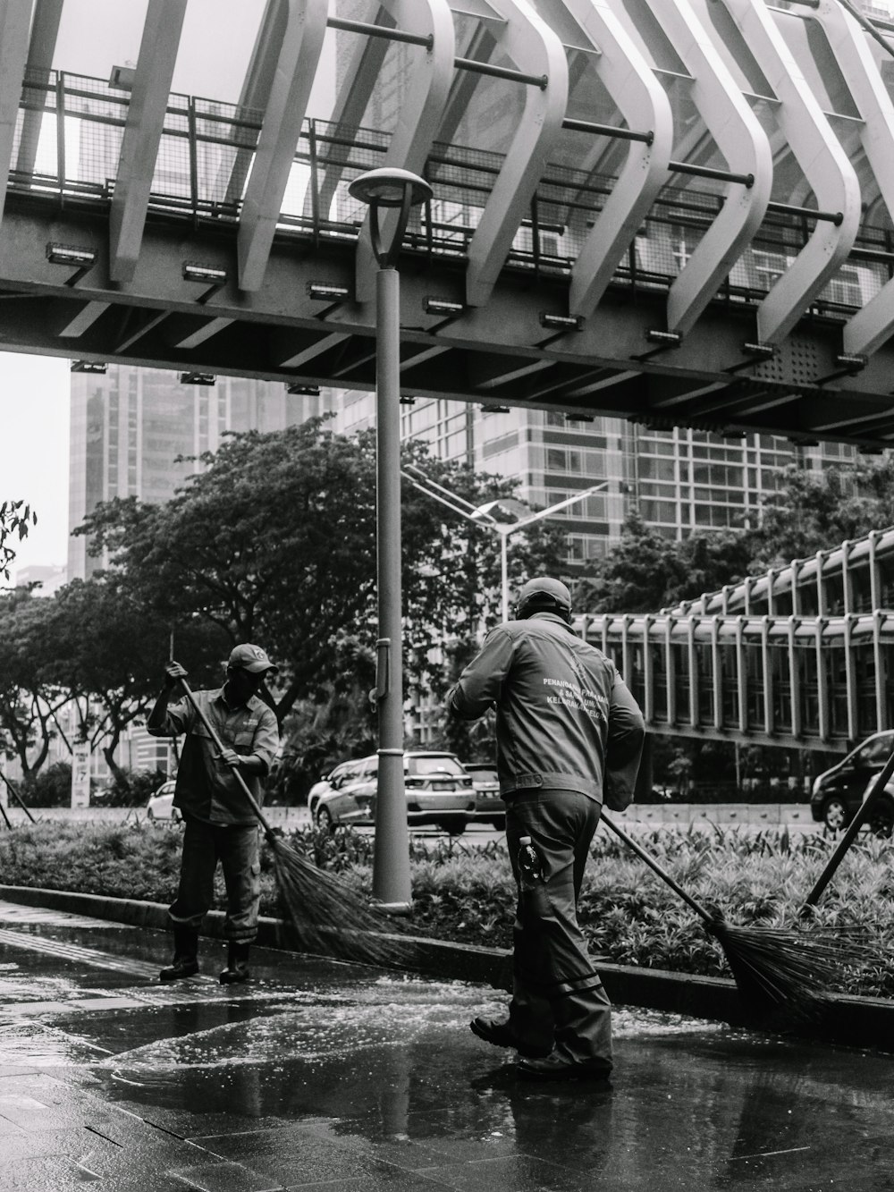 a black and white photo of a man sweeping the street