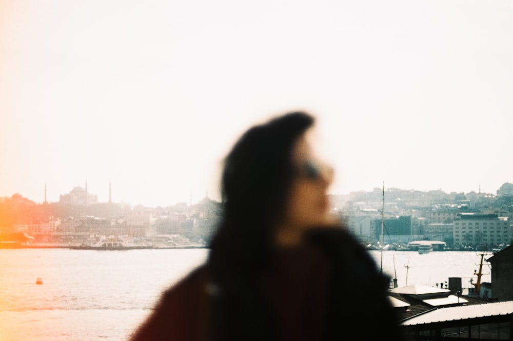 a blurry photo of a woman standing in front of a body of water