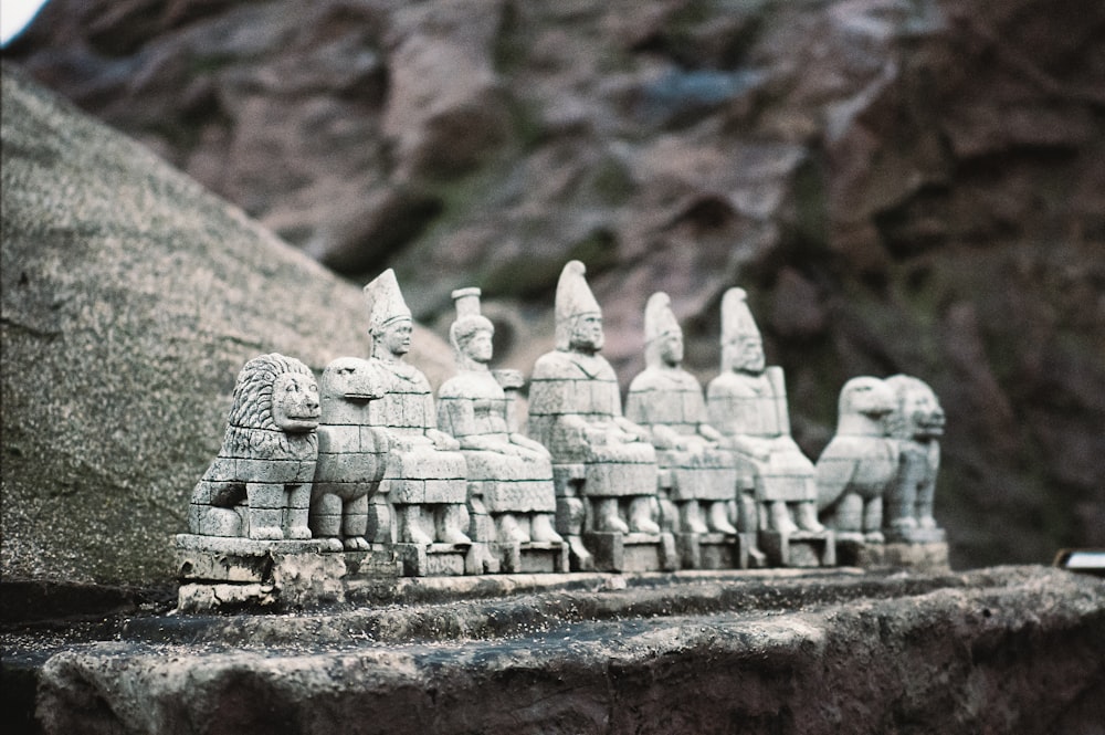 a group of statues sitting on top of a stone wall