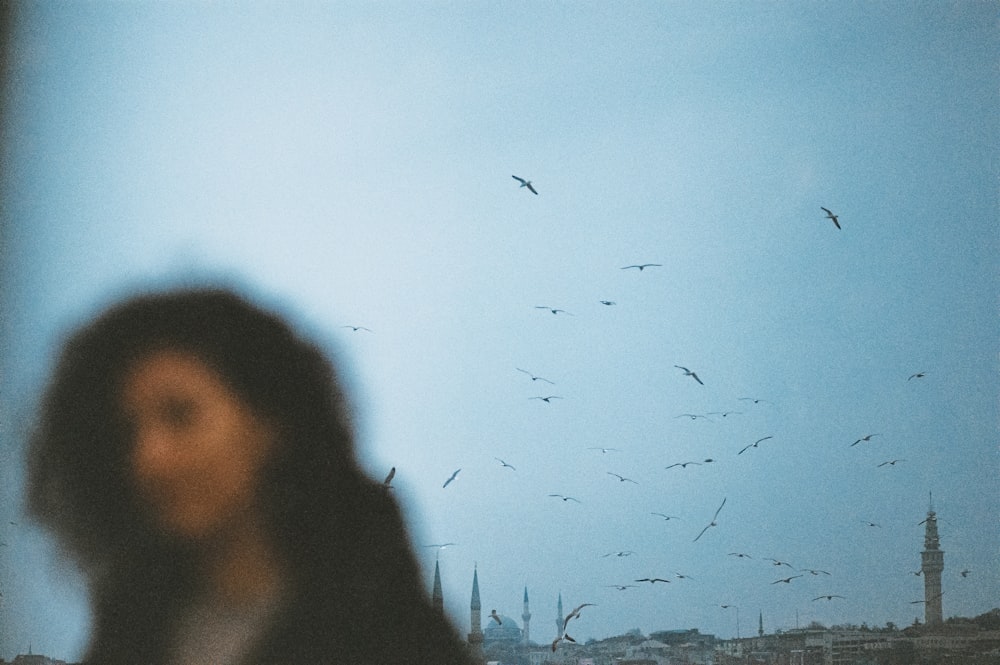 a blurry photo of a woman looking at a flock of birds