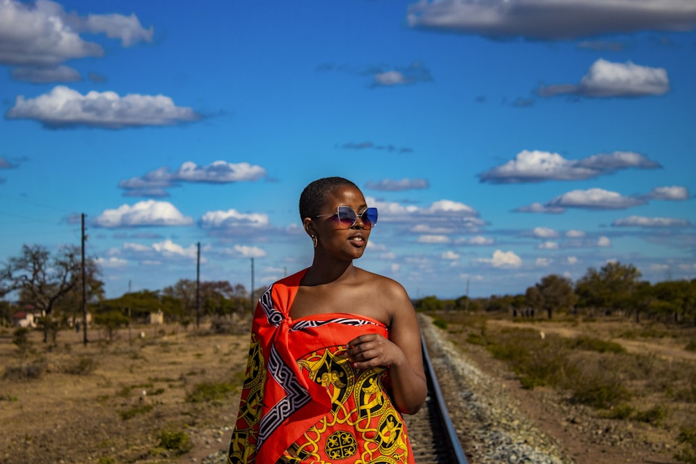 a woman in a colorful towel standing on a train track