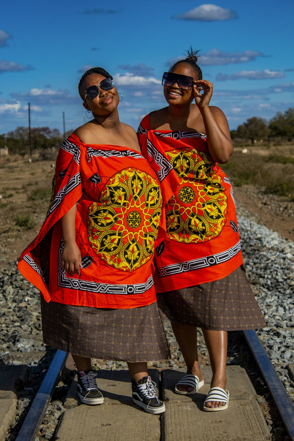 a couple of women standing next to each other on a train track