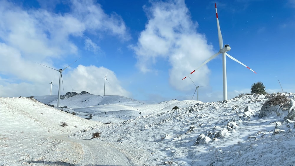 a snow covered hill with wind turbines in the background
