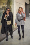 two women walking down a street talking on cell phones