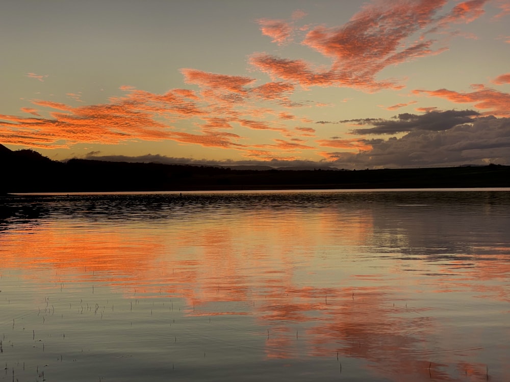 a sunset over a body of water with clouds in the sky