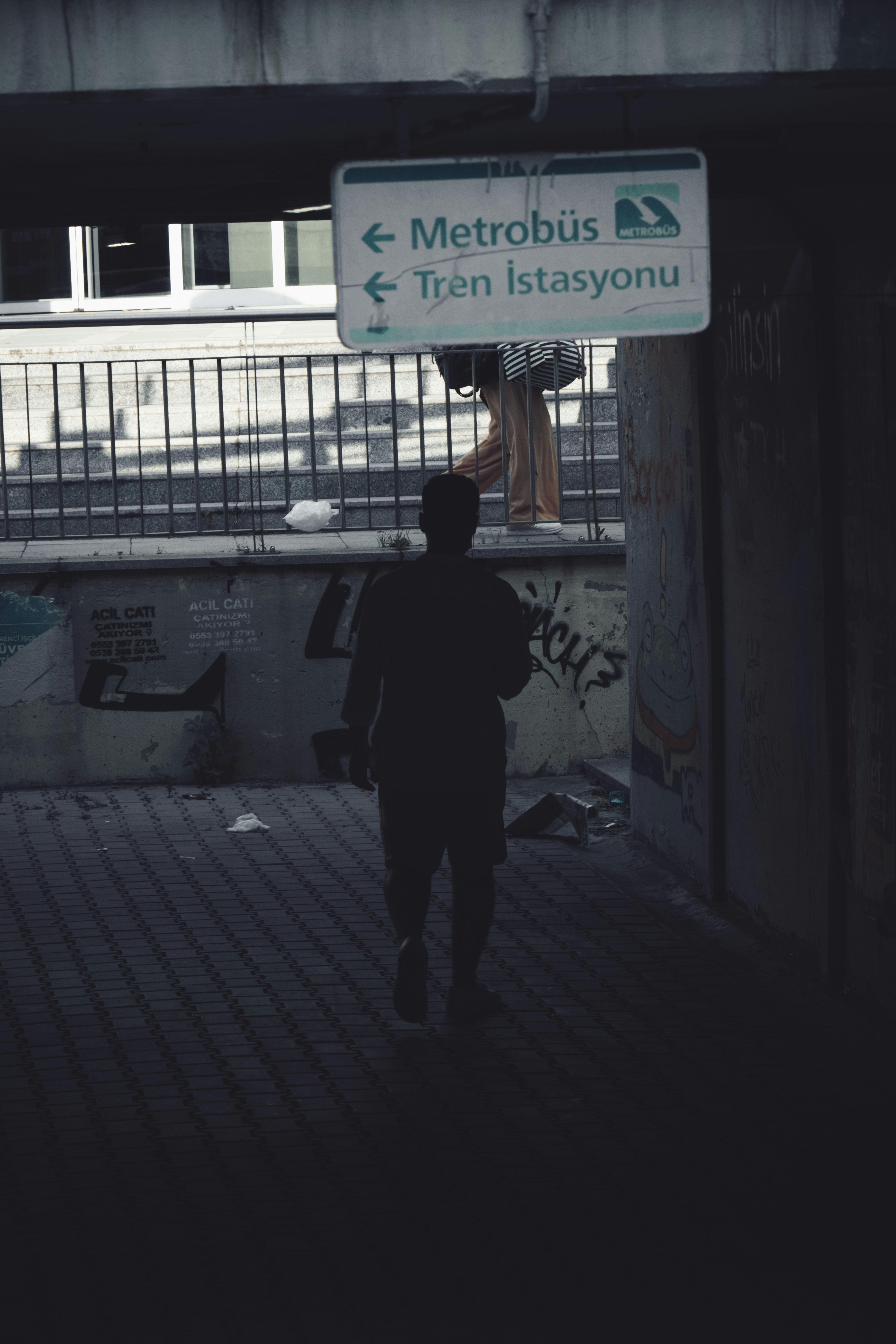 a man walking down a street under a bridge