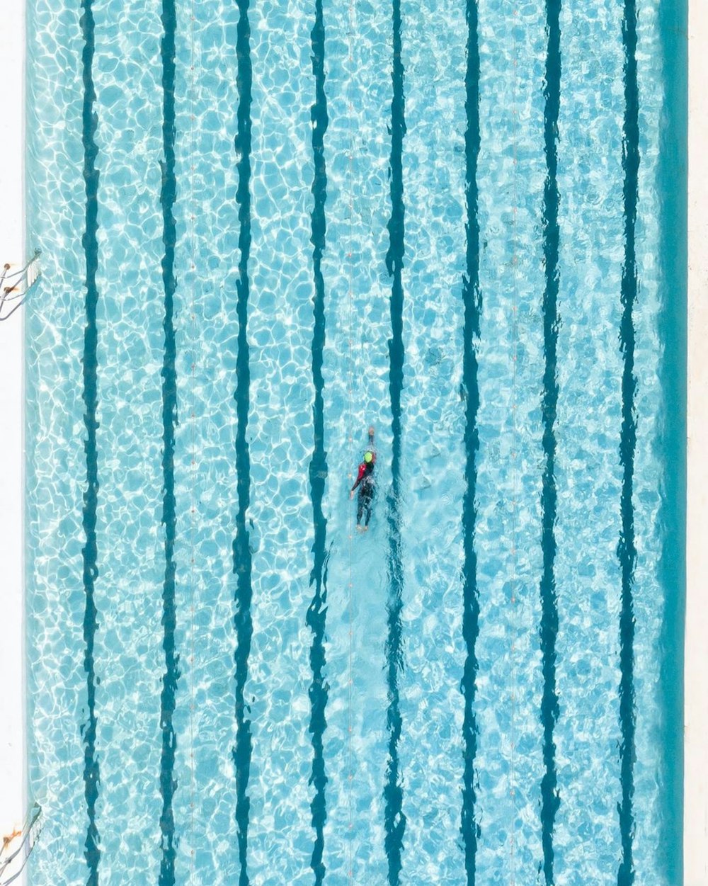 an aerial view of a man swimming in a pool