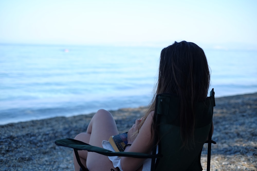 a woman sitting in a chair on the beach