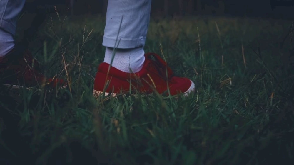 a person standing in the grass wearing red shoes