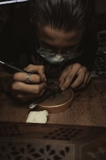 a man in a black shirt is working on a piece of wood
